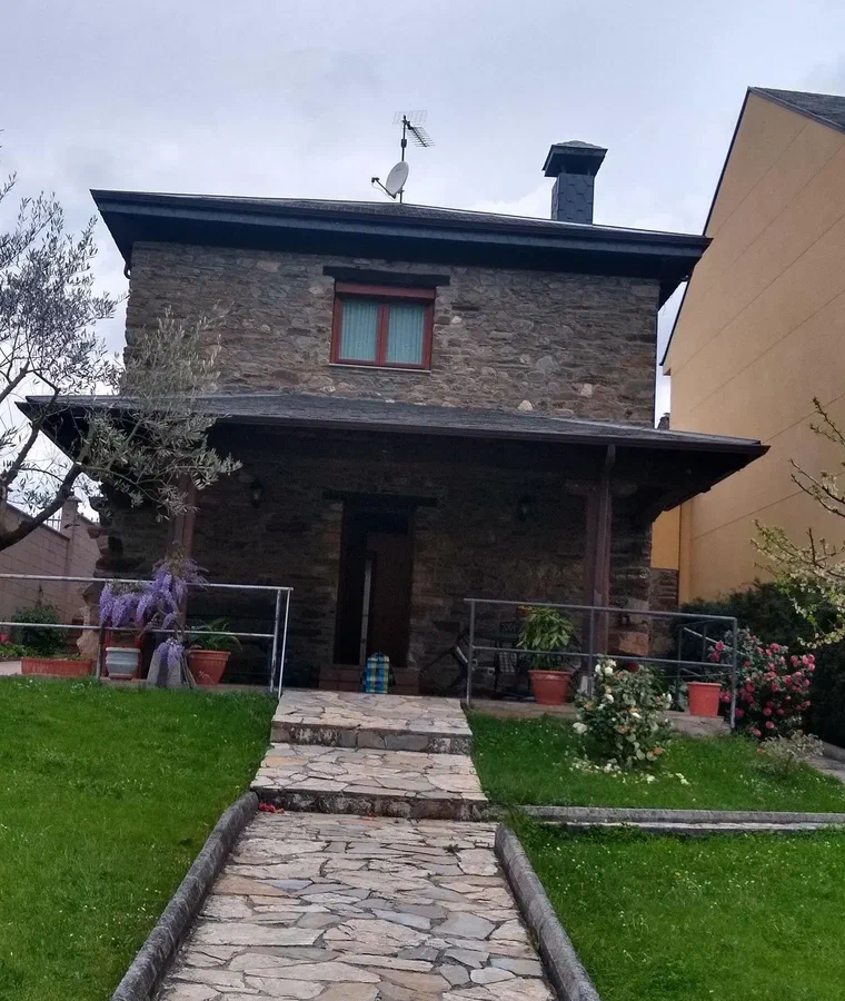 Camino de losas hasta la entrada de la casa, con glicinia en flor