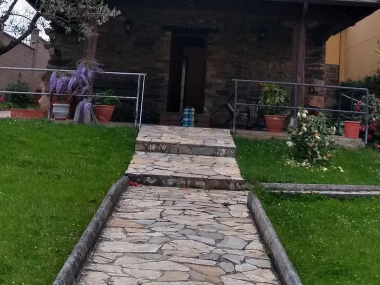 Camino de losas hasta la entrada, con glicinia en flor