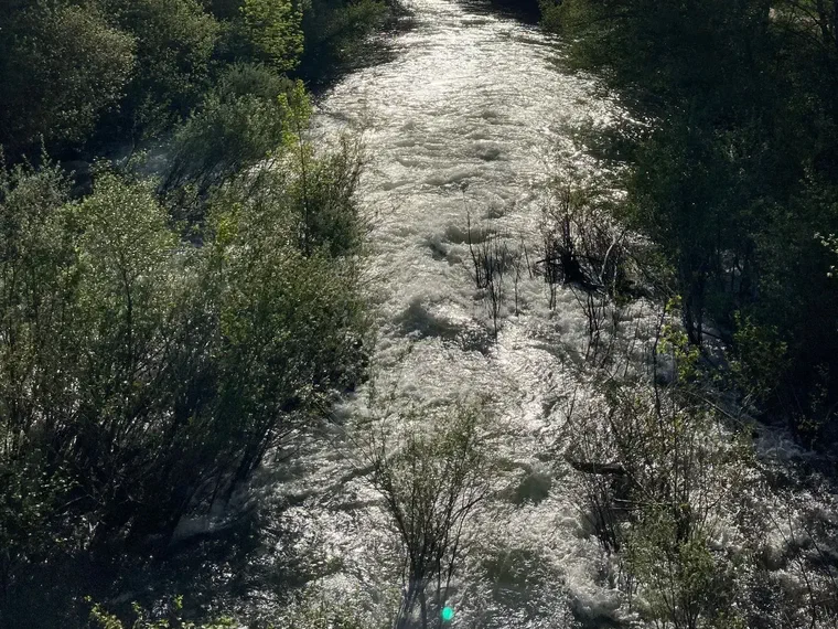 Río entre montañas y arboledas cerca de la casa